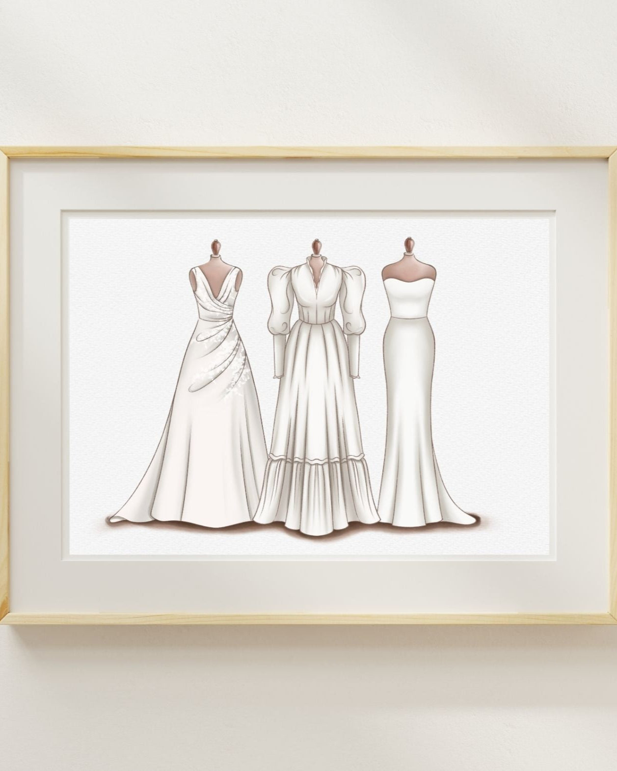 Framed illustration of three wedding dresses on a white wall