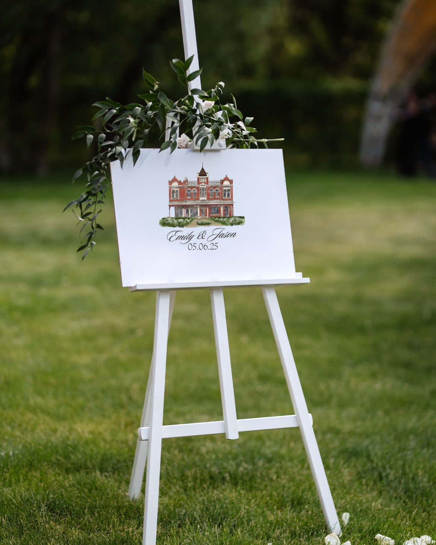 White easel with decorative sign featuring a building illustration on grass